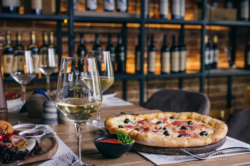 Pizza with prosciutto and olives with wine in restaurant