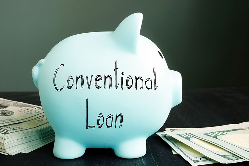 Learning Center 12 A light blue piggy bank labeled Conventional Loan sits on a table next to stacks of U.S. dollar bills, against a dark background.