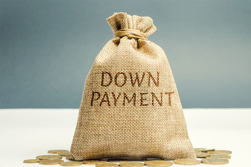 A burlap sack labeled DOWN PAYMENT stands upright on a white surface, surrounded by scattered gold coins, against a plain blue and white background.