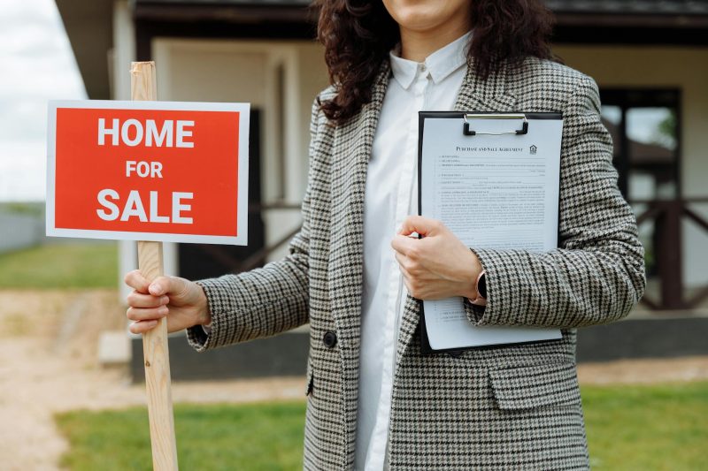 Blog 10 A real estate agent holding a home for sale sign