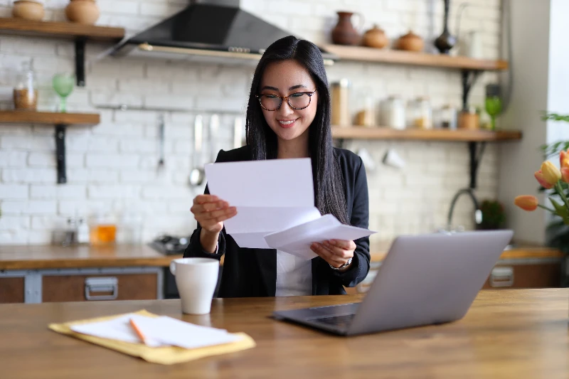 Blog 5 Businesswoman happily reads financial letter at a desk with laptop